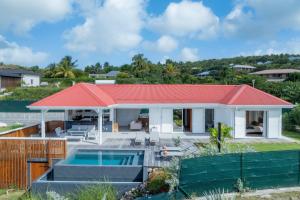 una casa con techo rojo y piscina en Villa Paloma, en Grand-Bourg