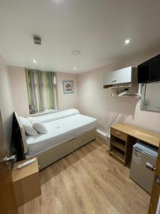 a small bedroom with a bed and a desk at Accommodation Plus in London