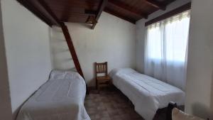 a bedroom with two beds and a window and a chair at Casa Mar de Cobo in Mar de Cobo