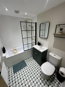 a bathroom with a toilet and a sink and a tub at Cosy Bollington Two Bed House in Bollington +17 photos