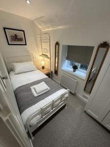 a bedroom with a bed with a mirror and a window at Cosy Bollington Two Bed House in Bollington