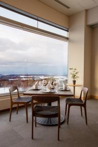 a dining room with a table and chairs and a large window at Rockwood Hotel & Spa in Ajigasawa