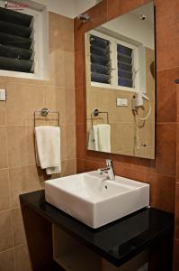 a bathroom with a sink and a mirror and towels at Sepoy Grande Mysore in Mysore