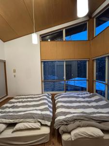 due letti in una stanza con ampie finestre di Nikko TOKORONO private villa, up to 6 people, 7 minutes by car from Tobu Nikko Station parking for 2 cars a Nikko