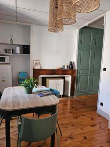 a dining room with a table and green cabinets at Appartement chez la fleuriste in Chaudes-Aigues +8 photos