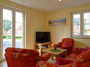 グロヴェにあるUrlaub Mit Hund Im Bernsteinhusのリビングルーム(赤い椅子、薄型テレビ付)