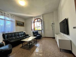 Gaggianoにあるvilla Geranio confortevole villa nei pressi di Milanoのリビングルーム(黒革の家具、薄型テレビ付)