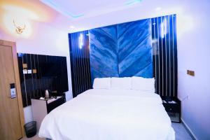 a bedroom with a large white bed with a blue wall at Cupid's Corner Luxury Hotel and Apartments in Benin City