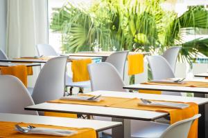 a row of tables and chairs with orange napkins at MB Boutique Hotel - Adults Recommended in Nerja