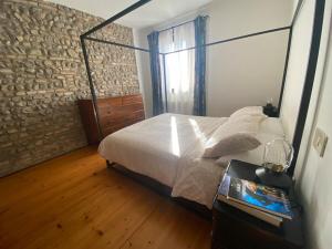 a bedroom with a bed and a brick wall at Petite Maison Wellness Palmanova in Palmanova