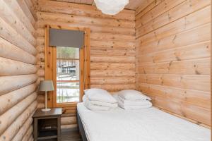 a bedroom with a bed in a wooden cabin at Yyteri Beach Lomakeskus, Havulinna 29 in Pori +2 photos