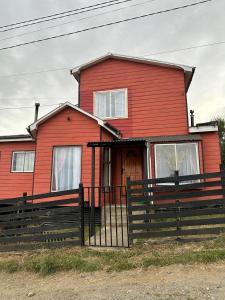 a red house with a fence in front of it at Casa in Castro