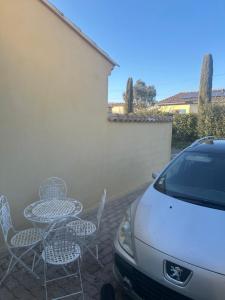 a patio with chairs and a table and a car at Appart type Hôtel, à 4 min du centre ville de Vaison-la-Romaine in Vaison-la-Romaine