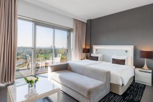 a bedroom with a bed and a couch and a large window at The First Collection Dubai Marina in Dubai