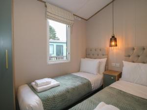 two beds in a small room with a window at Owl in Leominster