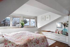 a white bedroom with a bed and two windows at Haus Riedel in Garmisch-Partenkirchen