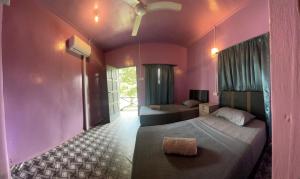 two beds in a room with pink walls at Osman homestay in Sukau
