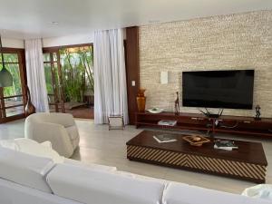 un soggiorno con un divano bianco e una TV a schermo piatto di Casa do Sol - Praia do Forte a Mata de Sao Joao