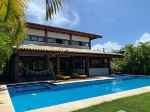 una villa con piscina di fronte a una casa di Casa do Sol - Praia do Forte a Mata de Sao Joao