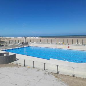 a large swimming pool next to a beach at Cosy gezellig app met aparte gastenkamer op 30meter van strand privé garage in Koksijde