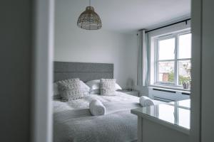 a white bedroom with a bed and a window at HighTide - 2 bed with parking, balcony & sea view. in Swanage