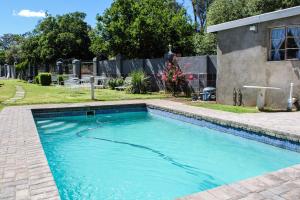 a swimming pool with blue water in a yard at Ebenhaeser guesthouse in Colesberg