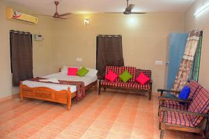 a bedroom with a bed and two chairs at AHRA Green Garden in Mahabalipuram +20 photos