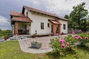 a white house with a patio and flowers at Ferienhaus Sofija in Vrtlinovec