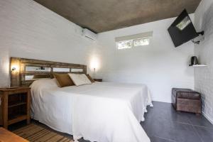 a bedroom with a white bed and a window at Hotel La Perla Domos in Punta del Este