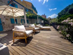 three chairs and an umbrella on a wooden deck at ECO Aparthotel The Dreamers's Club in Lumbarda