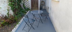 3 Stühle und ein Tisch vor einer Tür in der Unterkunft La Pivoine in Trouville-sur-Mer