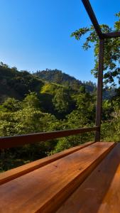 a wooden bench with a view of a mountain at Cabaña el Chapuzón montaña y rio, lugar fresco in Cedral