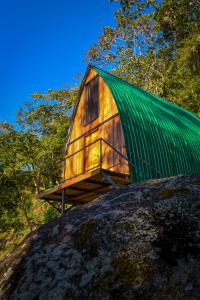 a tree house with a green roof on top of a rock at Cabaña el Chapuzón montaña y rio, lugar fresco in Cedral +10 photos