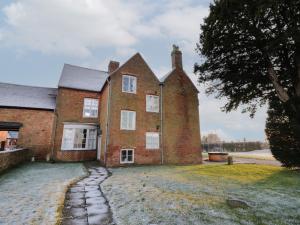 an old brick building with a tree in front of it at Dunnimere Farmhouse in Tamworth