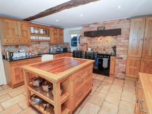 a large kitchen with wooden cabinets and a brick wall at Dunnimere Farmhouse in Tamworth