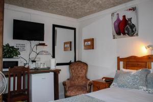 a bedroom with a bed and a desk and a chair at Ebenhaeser guesthouse in Colesberg