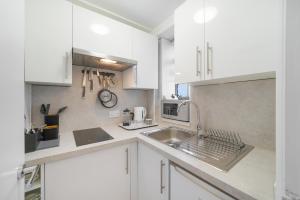 a kitchen with white cabinets and a sink at Executive Sloane Apartment 810 in London