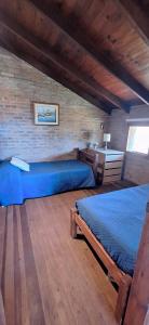 Un dormitorio con dos camas y una pared de ladrillo. en Oceanica la Paloma, en La Paloma