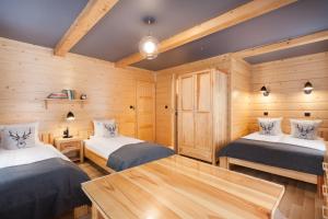 two beds in a room with wooden walls at Pokoje Gościnne BENITA in Zakopane