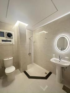 a bathroom with a toilet and a sink and a mirror at Bisan Apartment in Madinat Al Ashir min Ramadan +17 photos