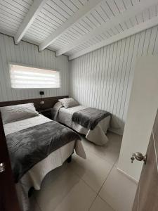 two beds in a room with a window at Cabañas Piedrablanca in Bucalemu