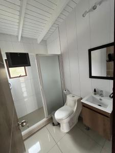 a white bathroom with a toilet and a sink at Cabañas Piedrablanca in Bucalemu +6 photos