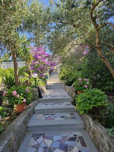 a garden path with pink flowers and trees at Apartments Nada in Sućuraj