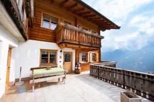 a wooden house with a balcony with a bench at Ferienwohnungen Kalchgruberhof in Ultimo