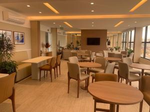 a waiting room with tables and chairs and a tv at Smart Convenções in Salvador