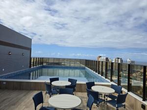 a balcony with tables and chairs and a swimming pool at Smart Convenções in Salvador