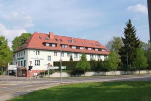 ein großes weißes Gebäude mit rotem Dach auf einer Straße in der Unterkunft Gasthaus & Hotel Grünhof in Frankfurt (Oder)