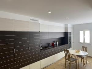 a kitchen with black and white cabinets and a table at Casa Conricado in O Grove