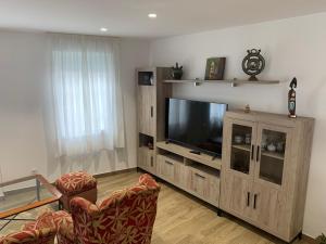 a living room with a large entertainment center with a flat screen tv at Casa Conricado in O Grove