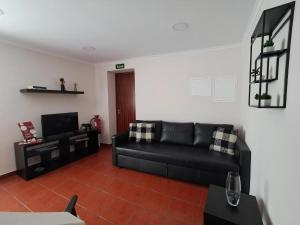 a living room with a black couch and a television at Haus Am Grünen Meer in Angra do Heroísmo